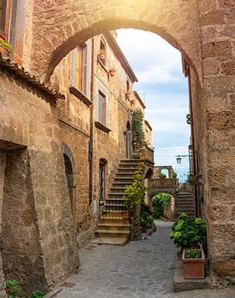 Photo d'une jolie ruelle avec un édifice et une ouverture en arche avec des pierres.