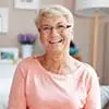 Photo de Marie-Jeanne, femme senior aux cheveux courts blancs, avec des lunettes et un chemisier rose.